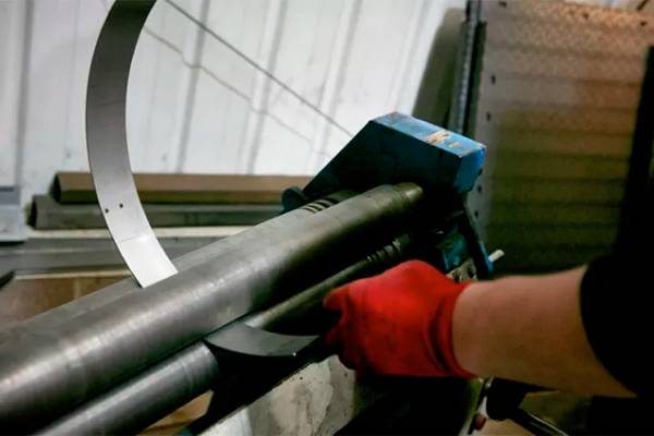 Worker using machinery in metal fabrication workshop.